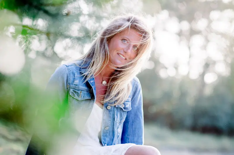 Portrait of a woman in a denim jacket seen through the foliage