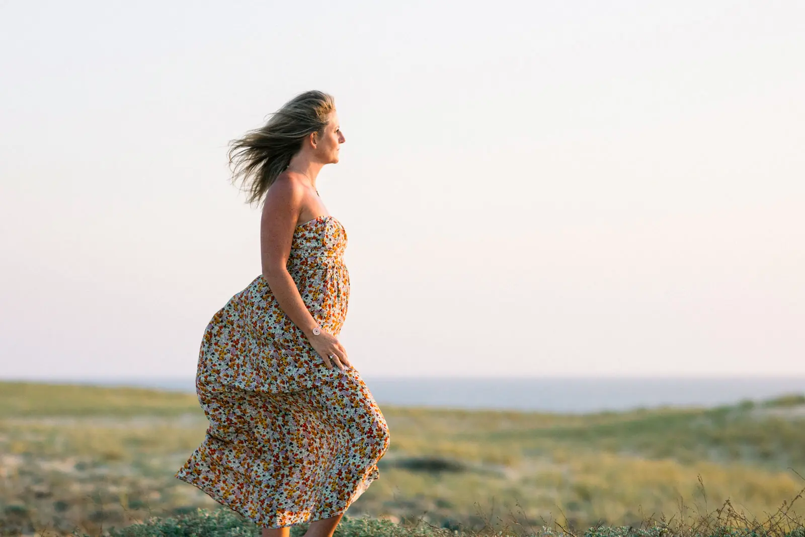 Woman in a long floral dress in the wind on the dune at Le Canon