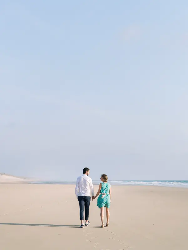 The couple walking hand in hand along the wide Lacanau beach