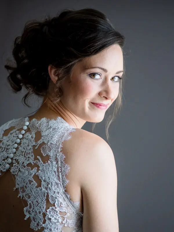 Bride's profile portrait showing her lace back and updo