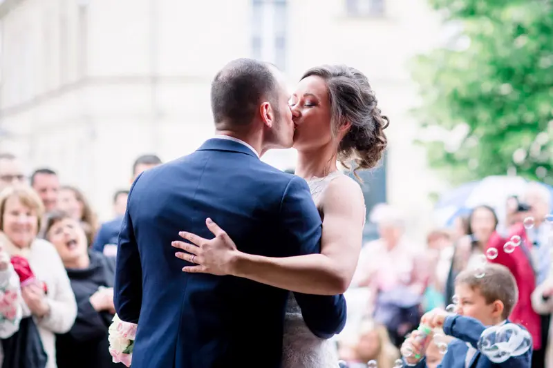 Bride and groom kissing as their guests applaud