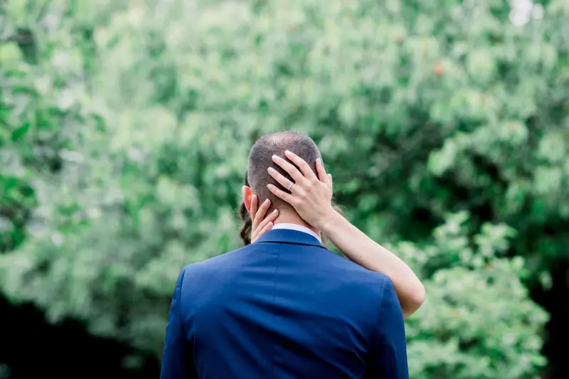 Bride's hand on the back of the groom's neck, seen from behind