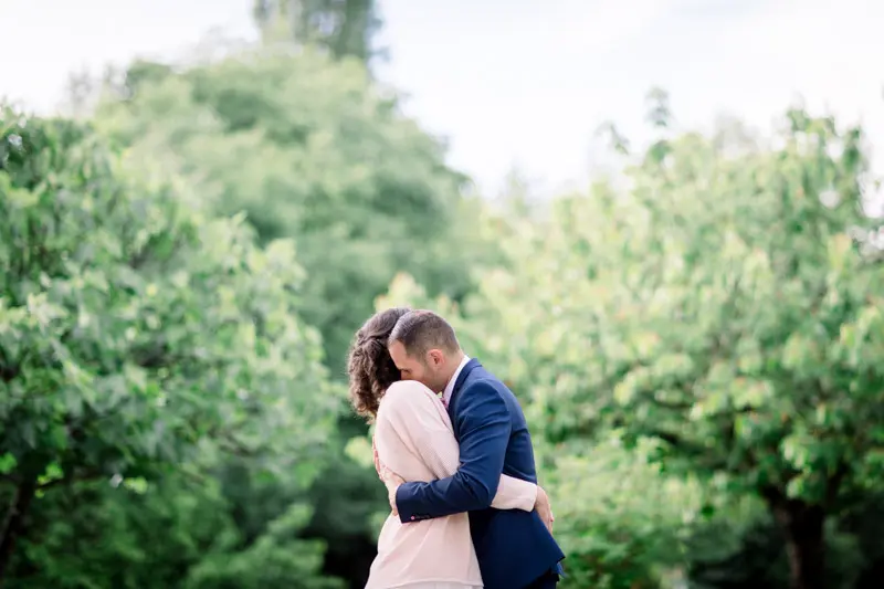 Bride and groom embracing in the distance among the manor's trees