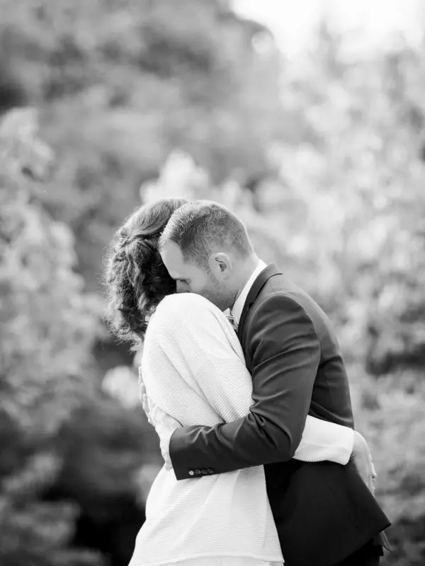 Bride and groom embracing in the garden during the evening, black and white