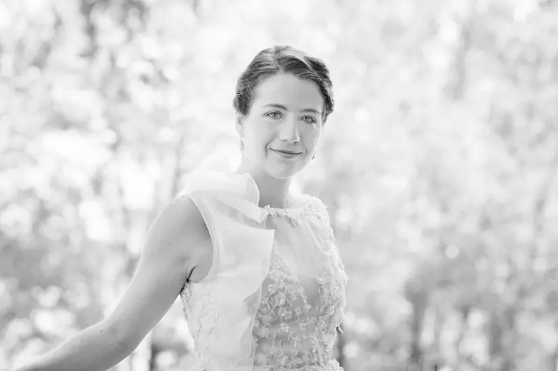 Black and white portrait of the bride in her lace gown against greenery