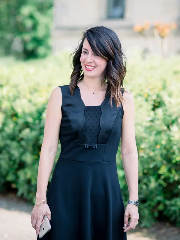 Alexandra Ambert in a black dress smiling in the château gardens