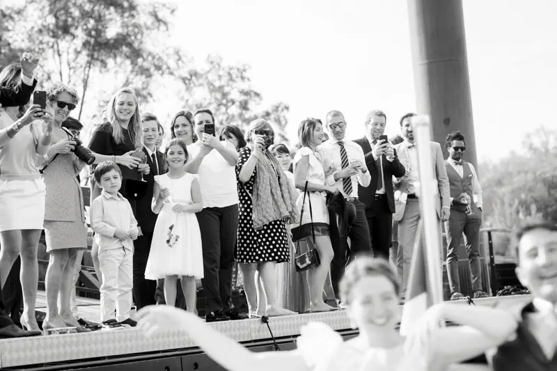 Guests waving from the boat deck during the wedding river trip, in black and white