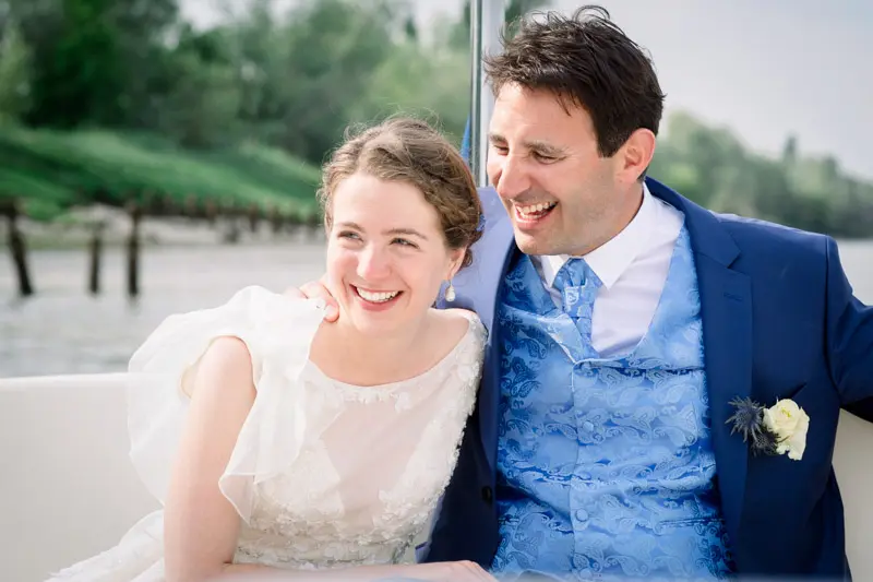The newlyweds laughing together, seated on the boat during the river cruise