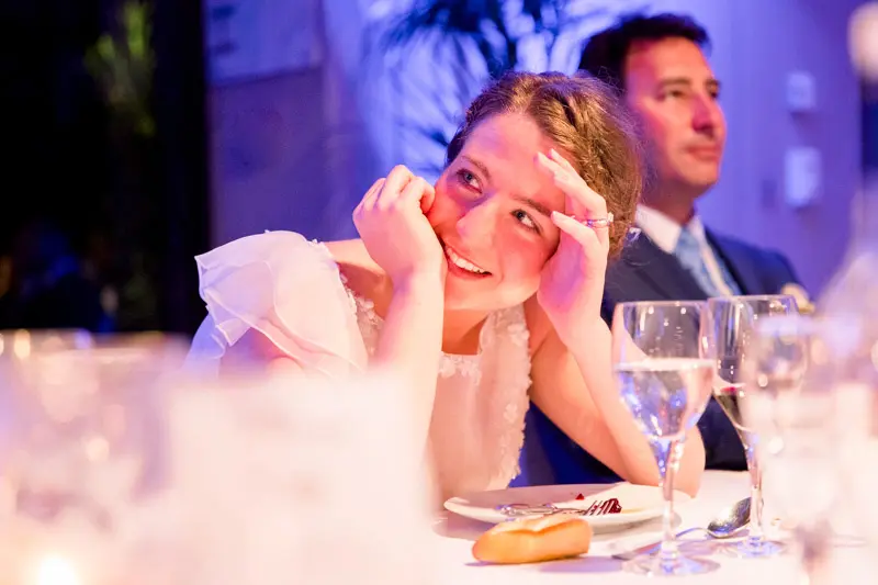 The bride, chin in hand, listening to the speeches during dinner