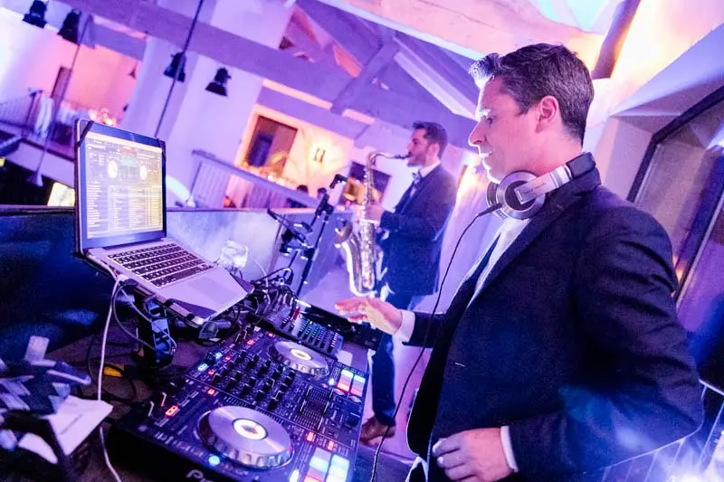 The DJ at the decks under violet lights at the wedding party