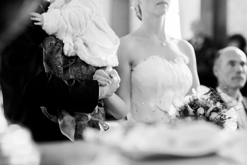 Bride seated during the ceremony with her bouquet, in black and white