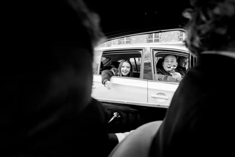 Bride and groom glimpsed through the vintage car window, in black and white