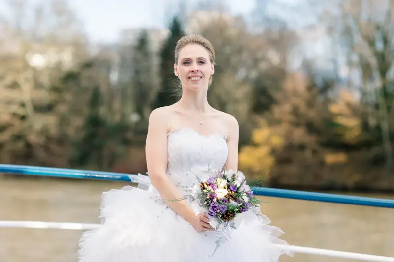 Bride in a tulle-skirted gown on the boat deck with a purple bouquet