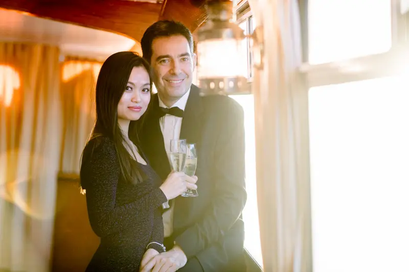 Groom and a guest posing with glasses of champagne on board