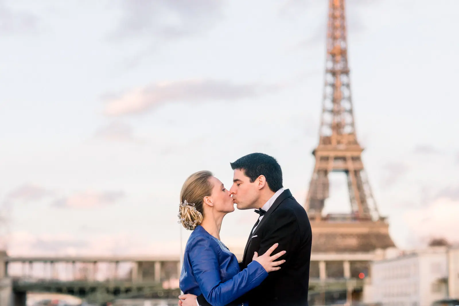 Bride and groom kissing by the Seine facing the Eiffel Tower in winter