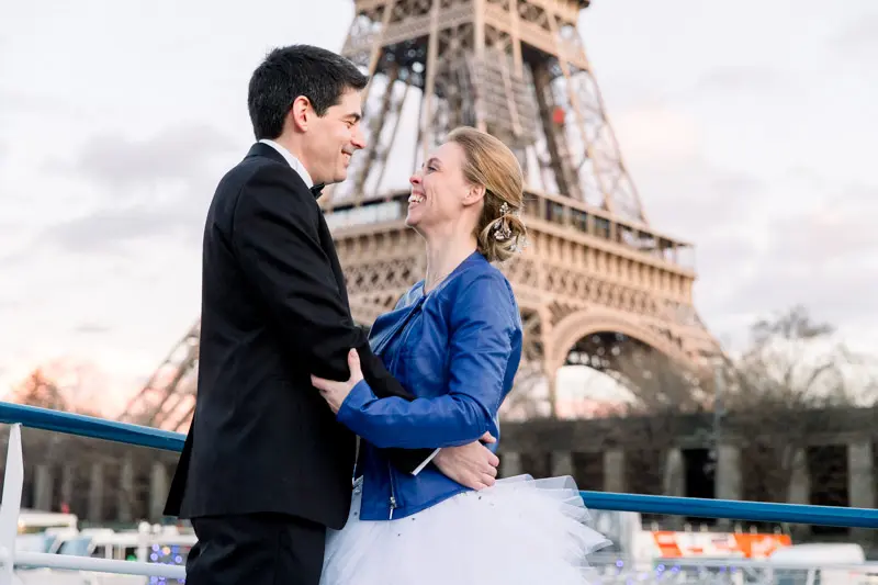 Bride and groom embracing on deck at the foot of the Eiffel Tower