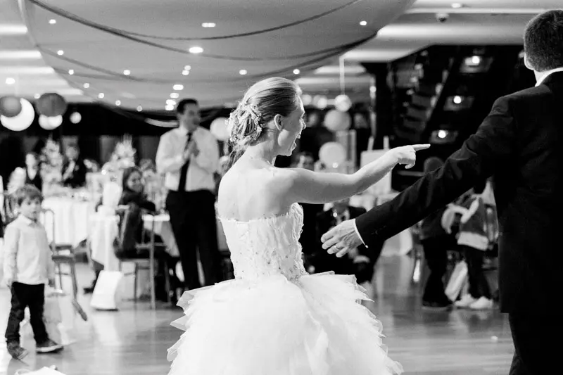 Bride dancing with outstretched arms in the boat's hall, in black and white