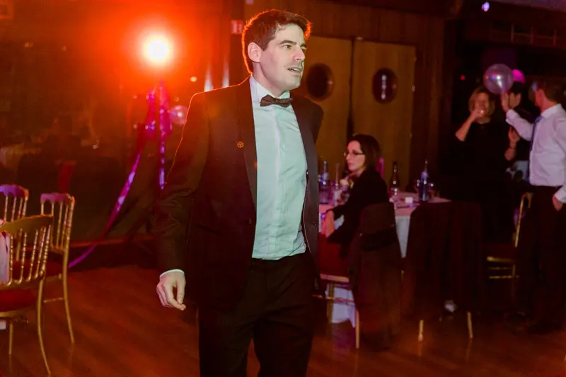 Groom in a bow tie on the dance floor under red lights