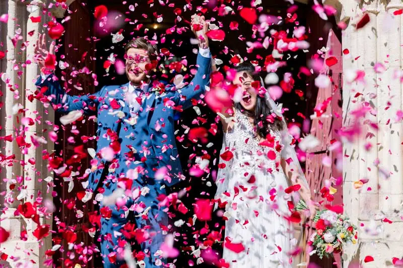 The newlyweds leaving the church under a shower of red and pink petals