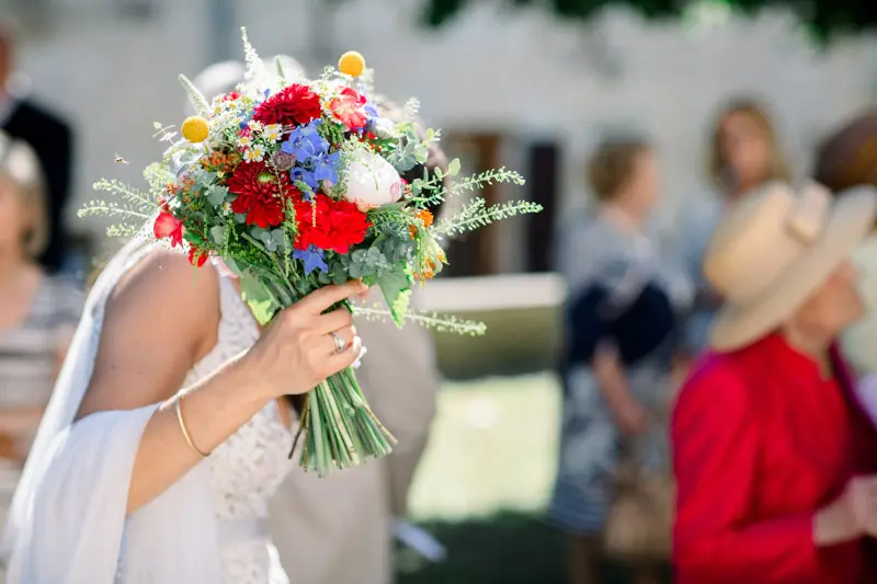 The bride holding a vividly colourful bouquet in front of the guests