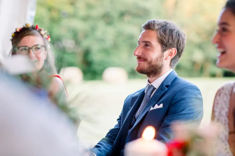 The groom smiling at the table during the outdoor meal