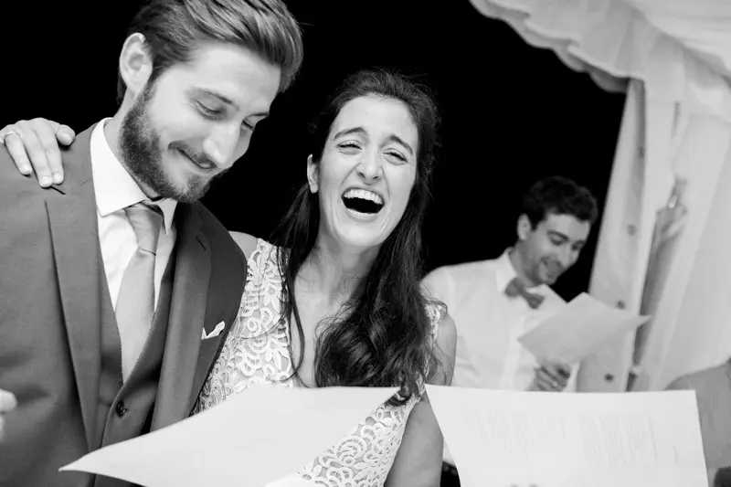 The newlyweds bursting into laughter while reading a speech, in black and white