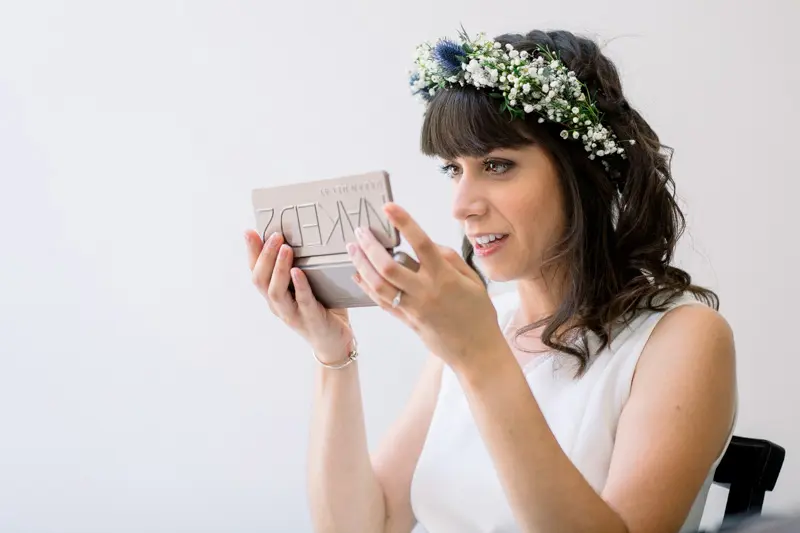 Bride in a flower crown opening a small gift box