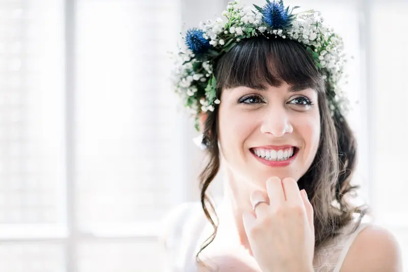 Laughing bride wearing a crown of blue thistles and white flowers