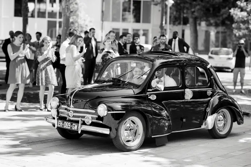 Guests around a decorated black vintage car, in black and white