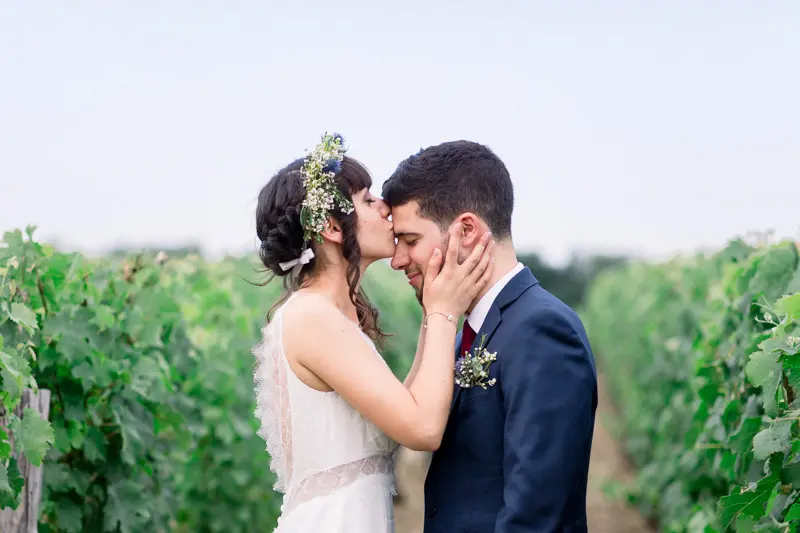Bride and groom kissing between the vine rows at Château Goudichaud