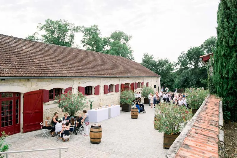 Wedding drinks reception by the red-shuttered wine stores at Château Goudichaud