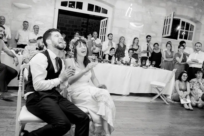 Couple laughing heartily in front of their guests during the evening, black and white