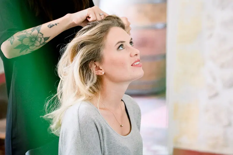 Bride having her hair styled, eyes raised, while getting ready