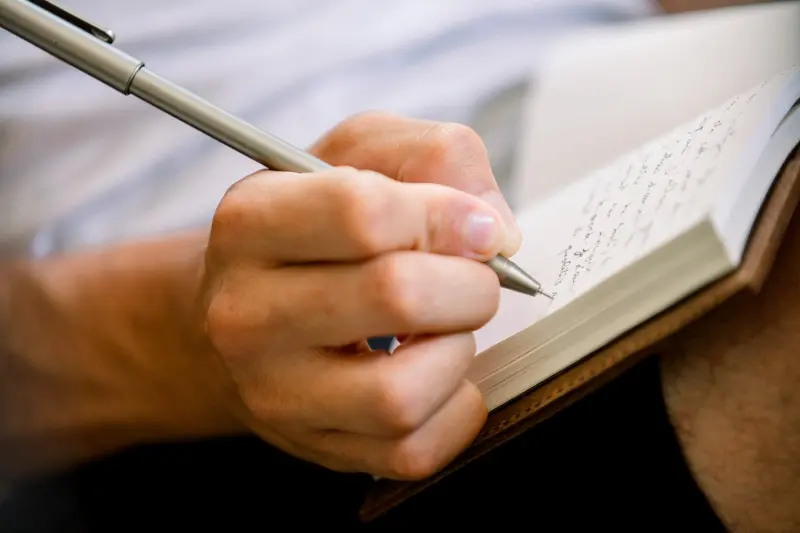 Groom writing a letter in a notebook on the wedding morning
