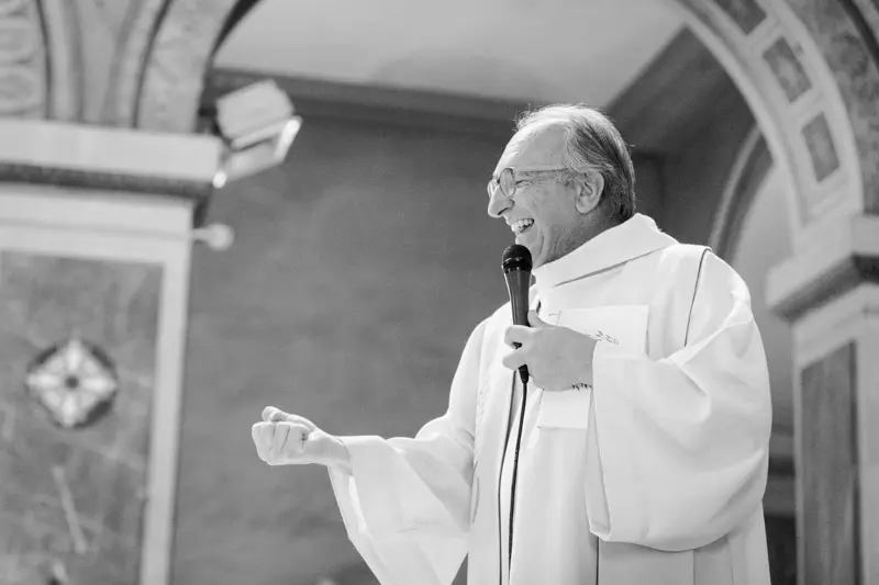 The priest speaking into a microphone during the ceremony at Saint-Martial, black and white