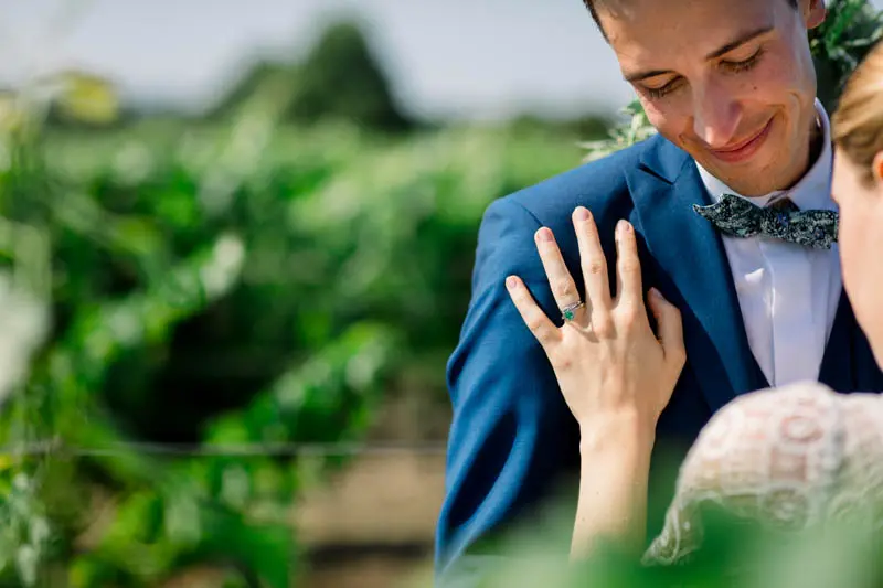 The bride's hand on the smiling groom's lapel in the vineyard