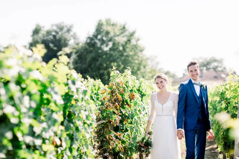 The newlyweds walking between the vine rows at Château Goudichaud