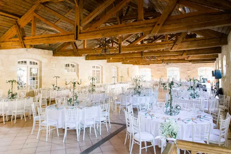 Château Goudichaud reception room set with round tables beneath wooden beams