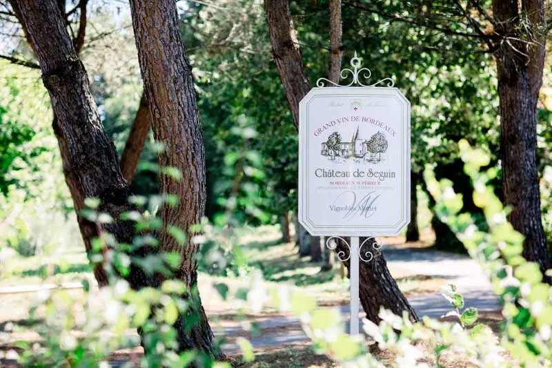 Entrance sign of Château de Seguin in the shade of the pines