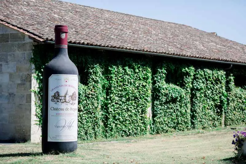 Giant wine bottle in front of the creeper-covered winery at Château de Seguin
