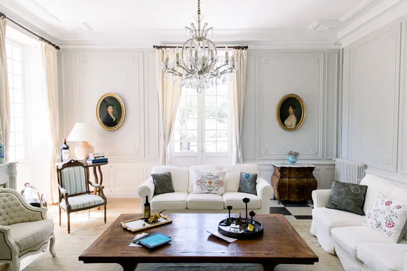 Bright drawing room at Château de Seguin with crystal chandelier and white sofas