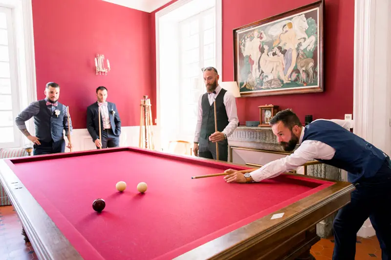 The groom and friends playing pool in the château's red billiard room while getting ready