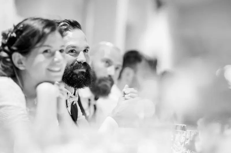 The groom and guests listening to the dinner speeches, in black and white