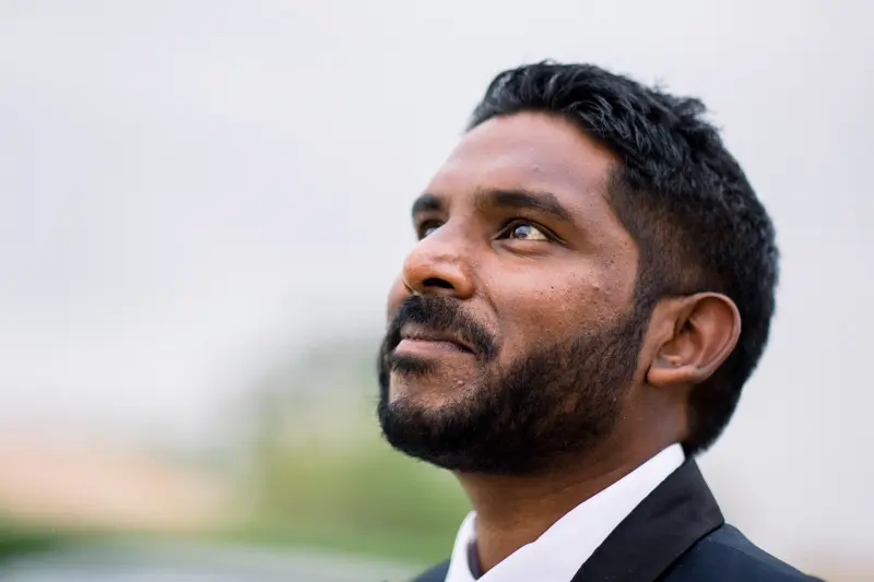 Portrait of the groom in a navy suit, gazing up at the sky