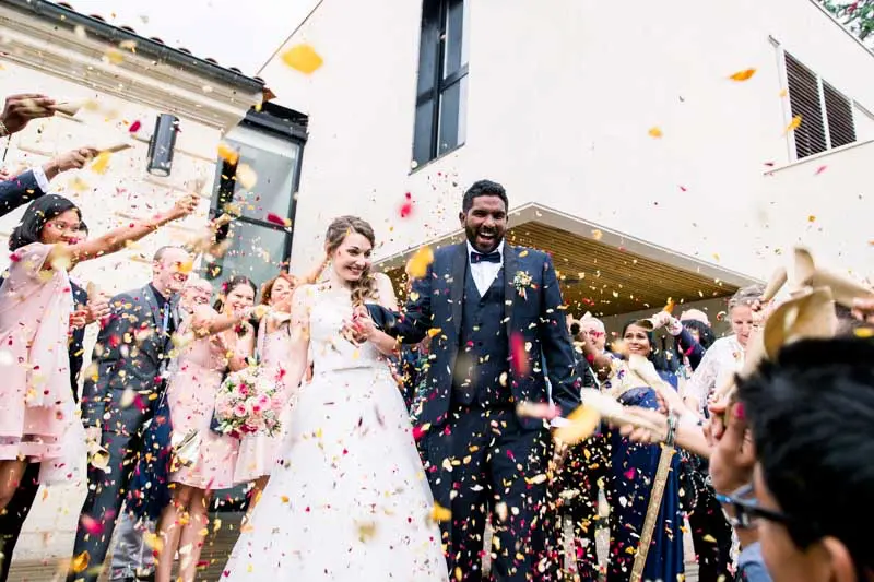 Céline and Perathipan walking out under a shower of confetti
