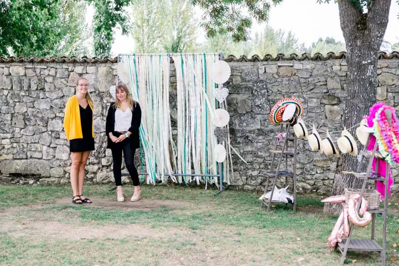Ribbon photo booth backdrop against a stone wall with two guests