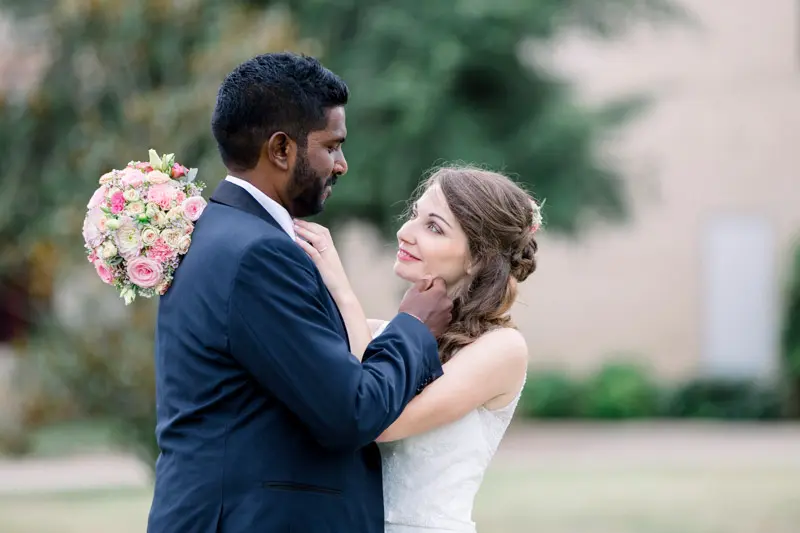 Bride touching the groom's face, rose bouquet in hand