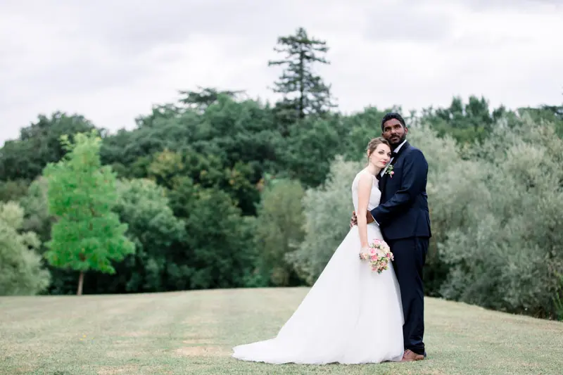 Couple embracing on the Manoir de Taillefer lawn with trees behind