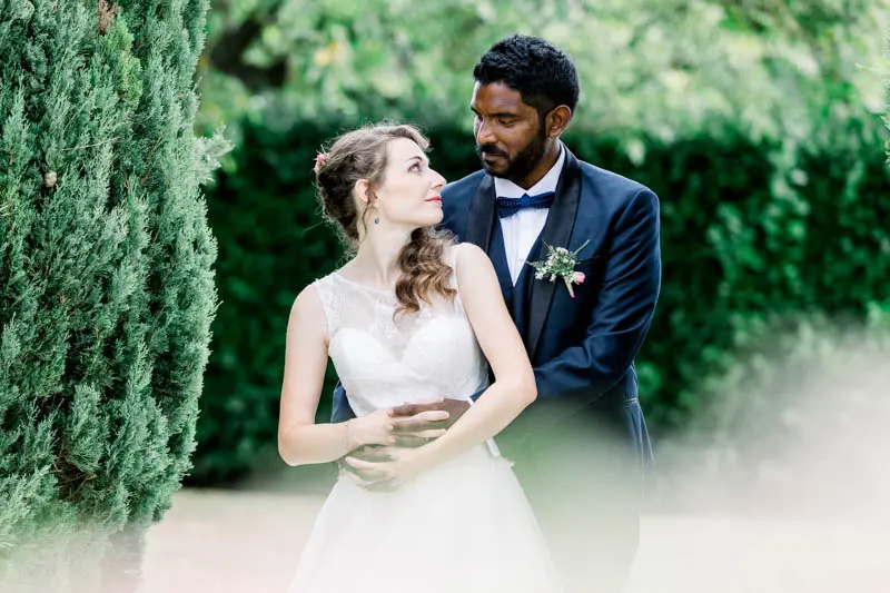 Smiling couple embracing between the cypresses at Manoir de Taillefer