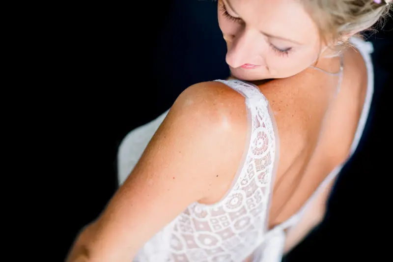 Lace back of the bride's gown as she glances down over her shoulder